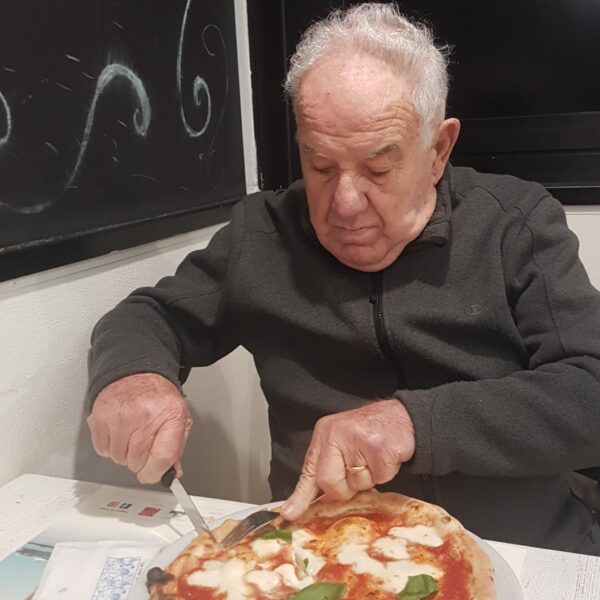 anziano che taglia una pizza margherita-progetto animatore sociale